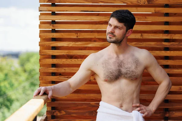 Otelin balkonunda havluyla güzel bir vücudu olan kendinden emin bir adam.