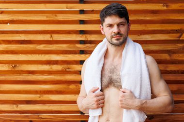 Çıplak gövdeli ve boynunda havlu olan kaslı bir adam..