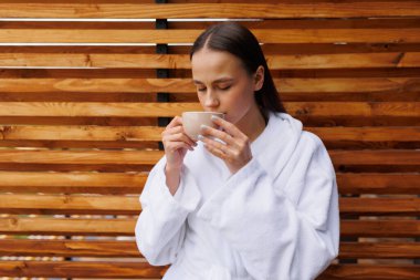 Bornozlu kadın spa tedavisinden sonra çay içiyor.
