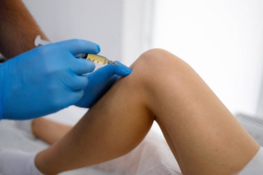 Doctor inject hyaluronic acid platelet rich plasma into the knee of young woman to walk without pain