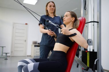 Female physiotherapist assisting woman training in rehabilitation clinic