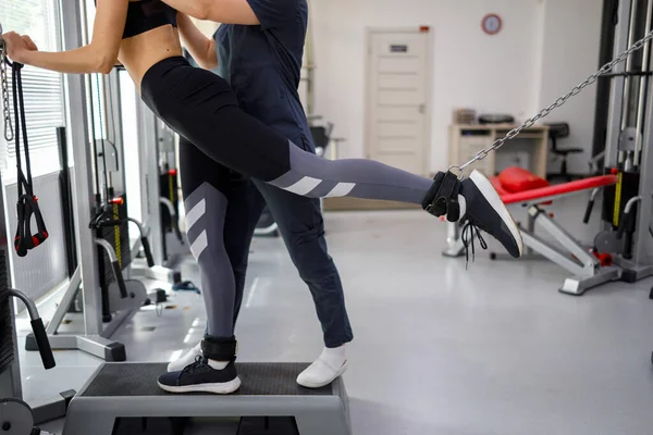 Kinesiologist helps a woman do exercises to strengthen her muscles. Rehabilitation doctor helps patient recover from injury