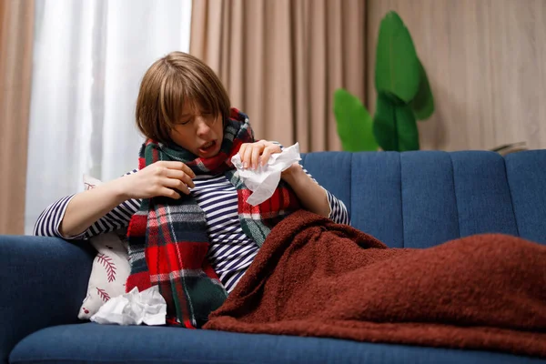 Flu sick young woman sneezes while lying on sofa