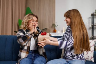 Kanepede oturan olgun bir kadın kızının hediyesiyle mutlu olur.