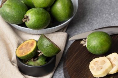 Dilimler ve siyah sedyede farklı boyutlarda doğranmış feijoa parçaları. Vitamin suyu hazırlama süreci