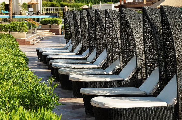 Kahverengi boş güneş pansiyonları yumuşak beyaz şilteler ve rattan gölgeliklerle sıralanmış.