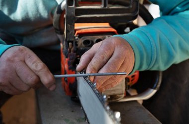 Bir adamın ellerine ve eski elektrikli testereye dikkatle odaklan. İnsan, elektrikli testerenin bıçaklarını yeniler ve keskinleştirir.