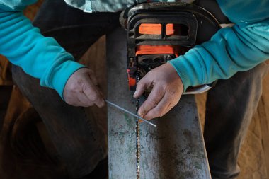 Bir adamın ellerine ve eski elektrikli testereye dikkatle odaklan. İnsan, elektrikli testerenin bıçaklarını yeniler ve keskinleştirir.