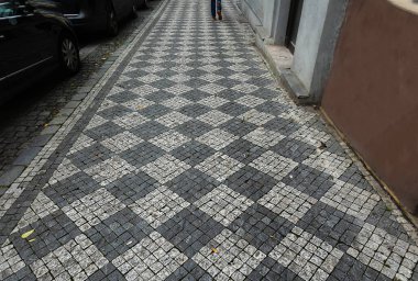 Kaldırımda döşeme döşeyen küçük karelerden geometrik arkaplan üzerine seçici odak