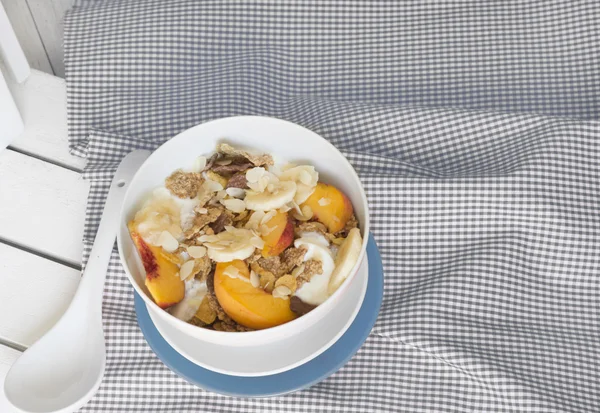 With bowl of cereal and fruit on orange tablecloth — Stock Photo, Image