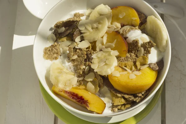 Frukostflingor av spannmål och frukt på vitt trä — Stockfoto