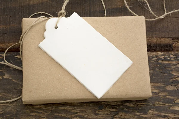 Gift box wrapped in recycled paper with label — Stock Photo, Image