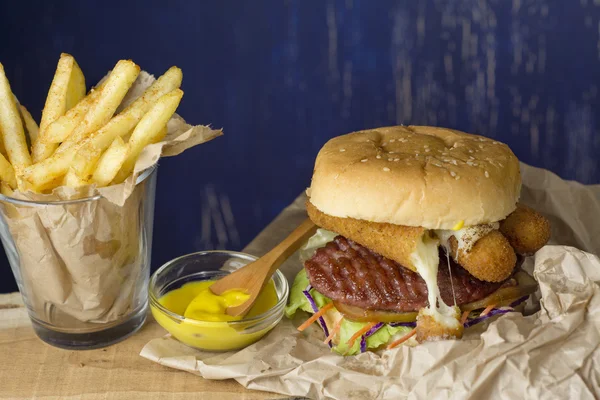 Hamburger, french fries in a paper wrapper , blue background — Stock Photo, Image