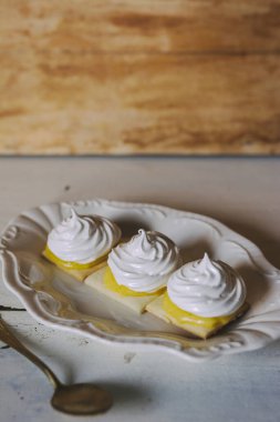 Çay saatinde servis edilen masanın üzerindeki zarif beyaz tabakta porsiyonlar halinde mini limonlu turta. Birleşik Krallık 'ın, Fransa' nın ve Amerika 'nın geleneksel mutfağı..