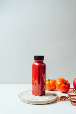Olgun elmalı domates ve pancarın yanında kırmızı smoothie şişede içilir. Sağlıklı vücut ve zihin için detoks diyeti. Sağlıklı gıda konsepti. Gri arkaplanda ön görünüm