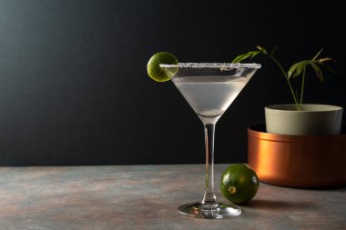 Tuzlu çerçeveli limonlu limonlu otantik margarita kokteyli, toprak renkli yüzey ve zarif koyu arkaplan, tekila, limon, acı portakal likörü ile süslenmiş lezzetli Meksika içeceği.