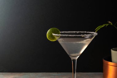 Tuzlu çerçeveli limonlu limonlu otantik margarita kokteyli, toprak renkli yüzey ve zarif koyu arkaplan, tekila, limon, acı portakal likörü ile süslenmiş lezzetli Meksika içeceği.