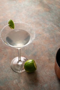 Tuzlu çerçeveli limonlu limonlu otantik margarita kokteyli, toprak renkli yüzey ve zarif koyu arkaplan, tekila, limon, acı portakal likörü ile süslenmiş lezzetli Meksika içeceği.