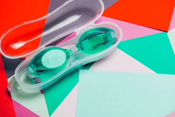 Zelené Mincovní Plavecké Brýle Gumovým Popruhem Červeném Zeleném Geometrickém Pozadí — Stock fotografie