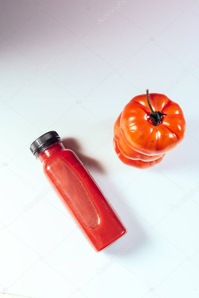 Red smoothie drink in bottle near ripe tomatoes. Detox diet for healthy body and mind. health food concept