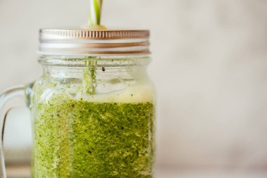 Elmalı ve limonlu yeşil smoothie cam kavanozda ıspanak ve arka planda saman,