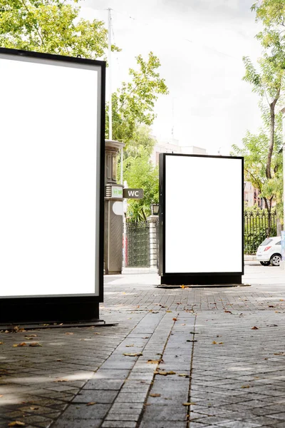 Outdoor mockup of a blank information posters on the sidewalk, empty vertical street banners templates ; billboard placeholder mock-up on a city boulevard in an alleyway outdoors