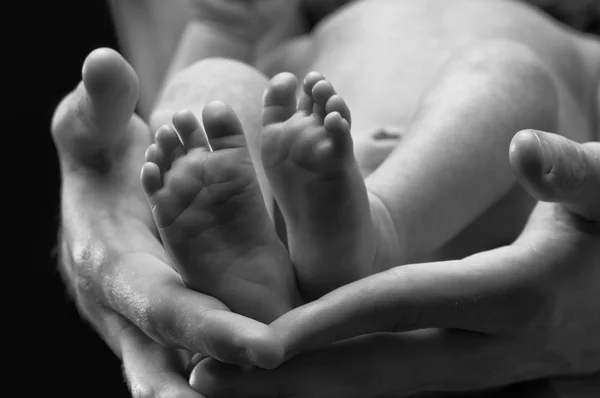 Baby pootjes en volwassen handen — Stockfoto