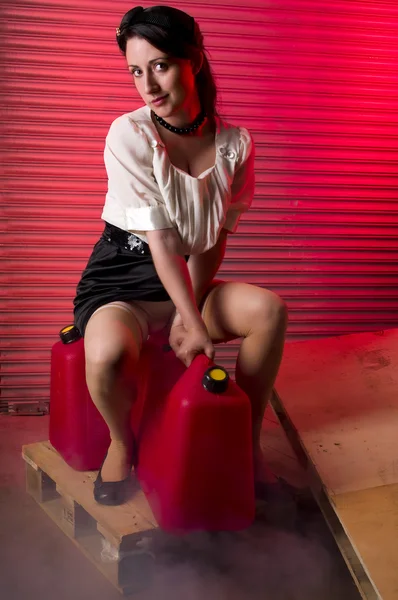 Woman standing in a garage wih smoke and gas containers. — Stock Photo, Image