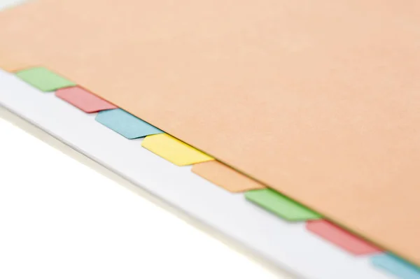 Close view of some colored index tabs lined up in a manila folder against a white background