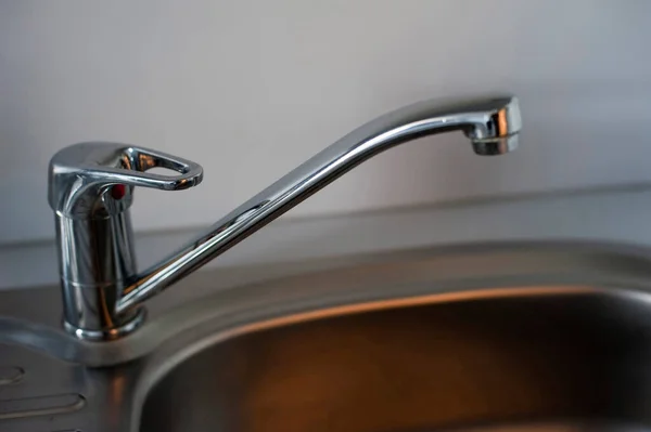 Detail of a modern chrome mono block kitchen tap over a stainless steel kitchen sink