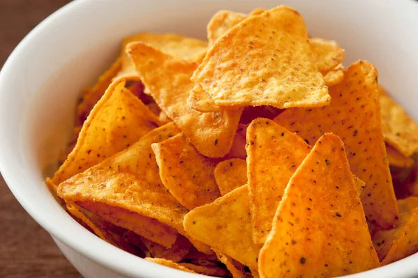 Bowl of traditional triangular corn tortilla chips or nachos for a delicious dipping snack or appetizer in a close up view