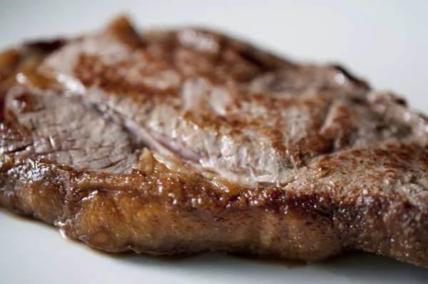 Fatty steak with a close up view of the cooked oily fatty rind on a portion of beef rump steak