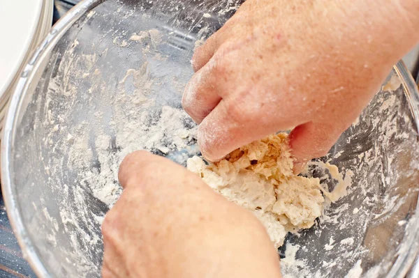 First person perspective top down view on pair of hands mashing up food in large round glass bowl