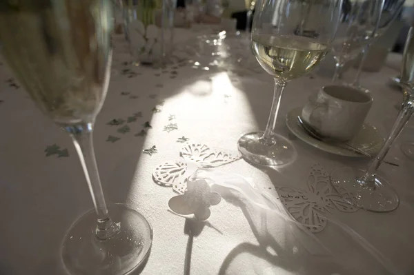 a dining table set up for a celebration meal with wine glasses and decorative confetti