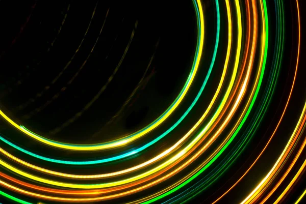 a pattern of green orange and yellow light trails moving around a central out of frame point