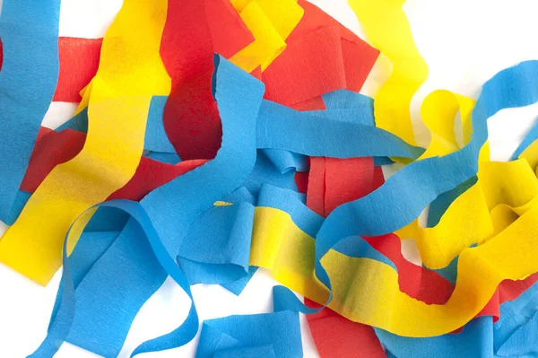 Pile of colorful paper party streamers in red, yellow and blue ready to decorate a festive venue for a celebration, full frame background