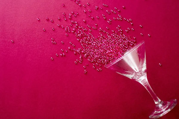 Cocktail glass party background on a festive red background with spilled beads in a decorative pattern and copy space