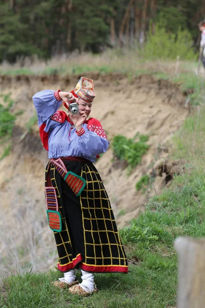 Kobieta w krajowych sukienki z aparatem na skraju lasu — Zdjęcie stockowe