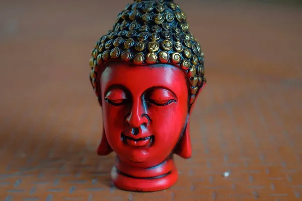 茶色の背景に黒と金色で描かれた仏像の頭 美しい赤い色の顔の彫刻や主仏像のストックフォト インドのバンガロールで撮影された画像 — ストック写真