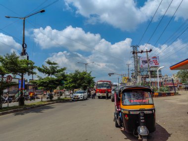 Gulbarga, Hindistan - 6 Ekim 2021, stok fotoğrafı Hint şehir manzarası, ulaşımı bekleyen insanlar, otomobil rikşovu, benzin pompasının önüne park edilmiş kırmızı renkli otobüs. Araç güneşli bir günde asfalt yolda..