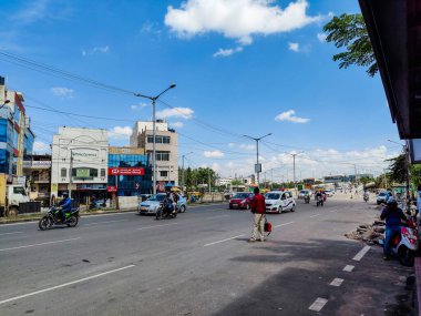 Bangalore, Hindistan - 21 Eylül 2021; Bnagalore 'daki işlek ipek tahta yolunun stok fotoğrafı, asfalt yolda ilerleyen araç, toplu taşımayı bekleyen çok az kişi var. Fotoğraf güneşli bir günde çekildi.
