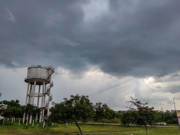 旧的生锈的白色漆成的水箱塔的照片 周围是蓝天下的绿树 中央是白云 连接到印度Gulbarga水箱的小径 — 图库照片