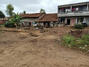 Kolhapur, Hindistan - 17 Temmuz 2021; Hindistan 'ın güzel yerleşim alanının stok fotoğrafı, piramit şeklindeki çatısı kil kaplı kırmızı tuğla ev yeşil ağaçlarla çevrili fayanslar. Hint kırsal yaşamı.