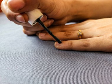 Siyah oje sürerken ya da tırnağına oje sürerken çekilmiş bir fotoğraf. Resim Hindistan, Karnataka, Bangalore 'da doğal ışık altında çekildi. nesneye odaklan.