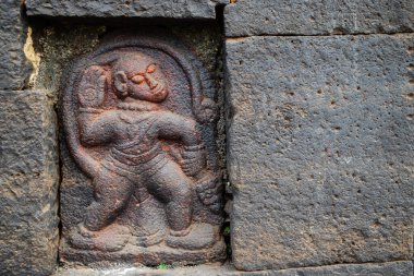 Kadim 'in gri taş duvara kazınmış Hindu tanrısı Hanuman' ın mahvolmuş arkeolojik heykelinin stok fotoğrafı. Fotoğraf Kolhapur, Maharashtra, Hindistan 'da güneşli bir günde çekildi. nesneye odaklan.