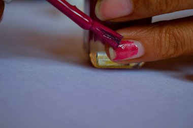 Pembe oje sürerken ya da tırnağına oje sürerken çekilmiş bir fotoğraf. Resim Hindistan, Karnataka, Bangalore 'da doğal ışık altında çekildi. nesneye odaklan.