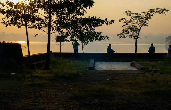 Sabahın erken saatlerinde Rankala bahçesindeki güzel manzaranın stok fotoğrafı, her yaş grubunda yoga, pranayama ya da göl kenarında meditasyon yapan insanlar lotus pozunda oturuyorlar. Arkaplanda altın rengi güneş ışığı