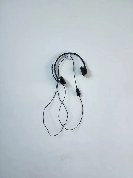 Στοκ Φωτογραφία Του Μαύρου Χρώματος Ακουστικά Που Κρέμονται Λευκό Χρώμα — Φωτογραφία Αρχείου