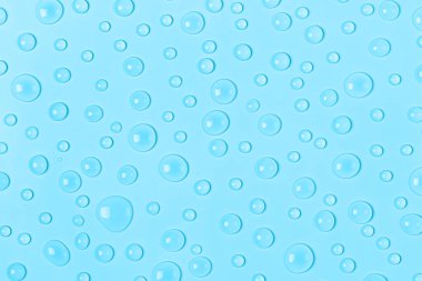 Su mavi bir zemine damlıyor. Su dokusu kapanıyor. Arkaplan camı su damlalarıyla kaplı. Su kabarcıkları.