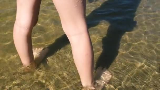 Közelkép a játékos gyerek lábak futó nedves homok sekély vízben a strandon érzés pozitív érzelem. Teljes HD lassított felvétel. Nyári szünet koncepció — Stock videók